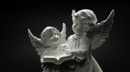 Fototapeta na wymiar Guardian angel on a dark background two angels are reading a book