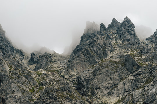 Detail of a mountain rock face, background or wallpaper picture of big wall rock climb, clouds and mist, stone and rock surface. Huge rock wall of granite in High Tatras, Slovakia.
