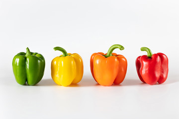 Colored bell peppers on white background. Green, yellow, orange and red pepper.