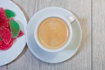 A cup of coffee and multi-colored marmalade, view from the top.