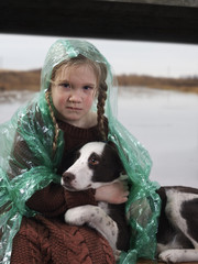 A child and a dog in a flood disaster area. The girl was crying, soaked in rain