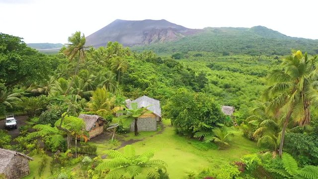 2019 - very good aerial over a jungle village on the island of Tanna reveals Mt. Yasur volcano in the distance, Vanuatu.