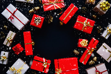 Christmas and New Year gifts boxes round frame, red and gold colors on black dark background - top view