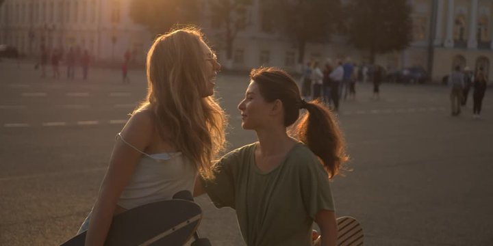 CINEMATIC SHOT of two young women hipsters millennials multinational girls outside talking. Slow motion