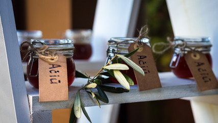 Small glass jars filled with honey, decorated with eucalyptus and a writing attached to them saying "Thank you"