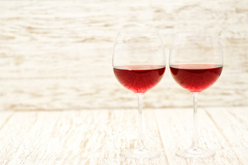 two glasses of red wine on a white wooden background, with copy space.