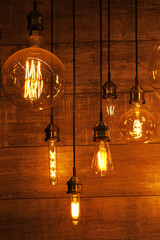 on a dark wooden background hang burning light bulbs of different shapes