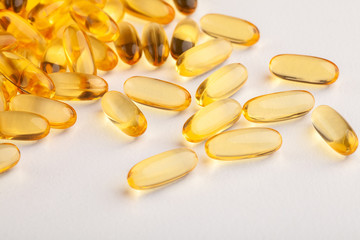 group of yellow fish oil capsules on a white table