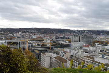 Germany, Houses of city stuttgart in valley surrounded by many hills and mountains forested with...