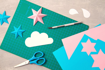 Top view over paper  cut tools, scissors, cutter, cutting mat, and crafted paper objects. DIY trendy project concept