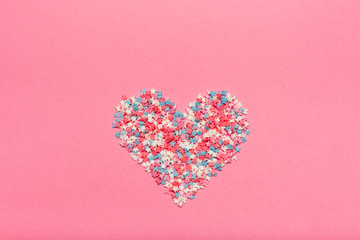 Colorful small candies on the pink background.