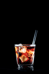 Cuba libre cocktail at the bar stand. Black background with place for text. Vertical