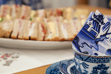 Tea cup with sandwiches in background