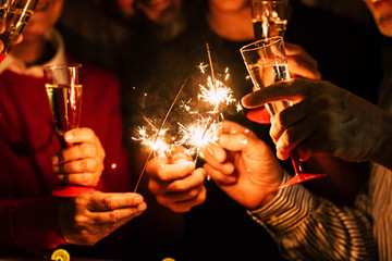 close up of people celebrate new year eve with sparklers and sparkling wine - nightlife concept -...