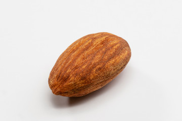 Close up shot of a single roasted almond on a white background.