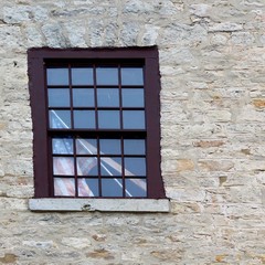 A single window on a brick building with the American Flag leaning in the window