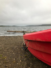 Closeup of a red row board sitting on a rocky shore
