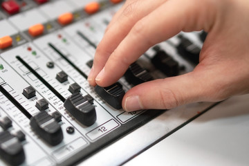 Male hand on control Fader on console. Sound recording studio mixing desk with engineer or music producer .