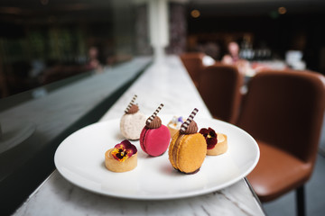 Close up of sweet colourful macarons on a white platy, served in a restaurant, symmetry