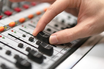 Fototapeta na wymiar Male hand on control Fader on console. Sound recording studio mixing desk with engineer or music producer .