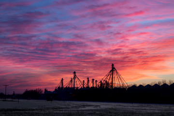 Fototapeta na wymiar Industrial Facility Silhouetted Against Fiery Red Sunset