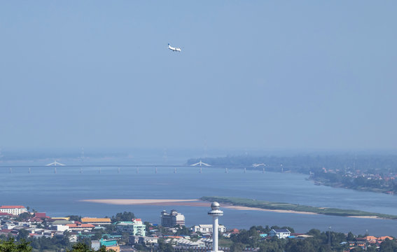 Aerial  landscape view above Mukdahan city with Ho Kaeo tower of Mukdahan during white passenger airplane landing to Savannakhet airport Laos over Mekong river border between Thai - Laos with second T