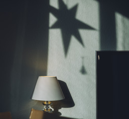 Abstract living room image with tabletop lamp, corner of a tv and shadow of a christmas star