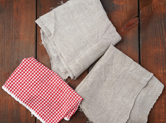 white red checkered kitchen towel and gray linen napkins on a brown wooden background