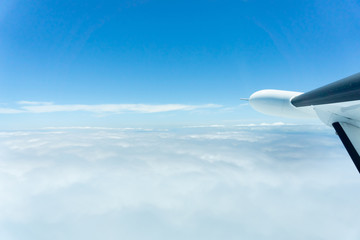 Naklejka na ściany i meble Through window of small plane flying above clouds,