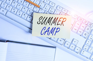 Word writing text Summer Camp. Business photo showcasing supervised program for children conducted during the summer White pc keyboard with empty note paper and paper clips above white background