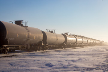 Naklejka premium Line of Black Railroad Tank Cars in Winter With Snow and Blue Sky