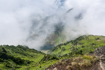 View of a mountain lake from the top of the mountain through the fog