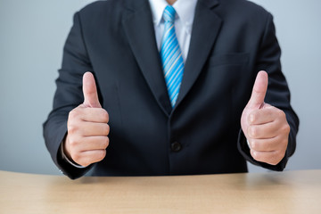 Business men wear suits sitting at desks and showing thumbs up