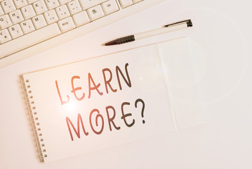 Conceptual hand writing showing Learn More question. Concept meaning gain knowledge or skill studying practicing White pc keyboard with note paper above white background