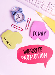 Writing note showing Website Promotion. Business concept for increase exposure of a website to bring more visitors Flat lay with copy space on bubble paper clock and paper clips