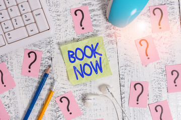 Word writing text Book Now. Business photo showcasing Make a reservation in hotel accommodation or airplane ticket Writing tools, computer stuff and scribbled paper on top of wooden table