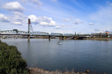 Fototapeta premium A lonely boat on Willamette River and Hawthorne bidge in Portland Oregon.