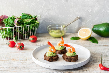 Canapes with avocado mousse and spicy shrimp on brown bread