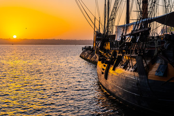 HMS Surprise ship, a tall modern replica of HMS Rose docked at Maritime Museum on the waterfront harbor bay in San Diego, Southern California at sunset.