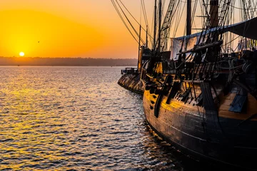 Fotobehang HMS Surprise ship, a tall modern replica of HMS Rose docked at Maritime Museum on the waterfront harbor bay in San Diego, Southern California at sunset. © Debbie Ann Powell
