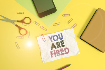 Text sign showing You Are Fired. Business photo text Getting out from the job and become jobless not end the career Paper sheets pencil clips smartphone scissors notebook colored background