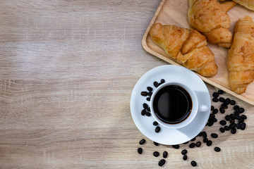 Coffee in white cup with coffee bean and croissants on wooden retro background, Breakfast concept