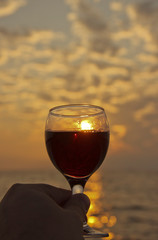 glass of red wine in his hand. Romantic day by the sea at sunset. The concept of wedding or Valentine Day celebrations.