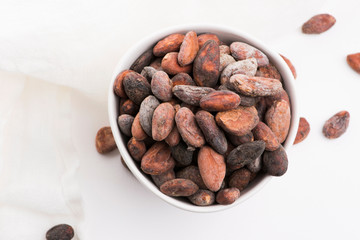 Bowl of cacao beans on a white background