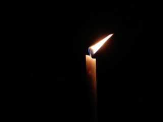 one burning candle against black background