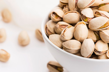 Bowl of roasted pistachios on a white background