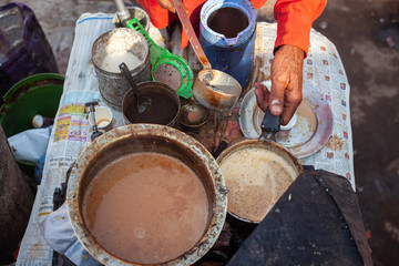 A man making chai on the street in india. Chai is a milk tea with spices like ginger cardamom black peper or cloves