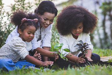 Save world concept - Mother and daughter are planting fun little trees on the fence of his house.