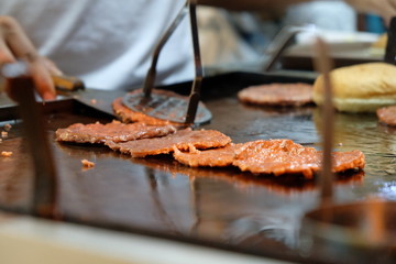 Cooking beef and chicken burgers on grill by night - Street food concept with mobile barbecue station open air in Sabah, Malaysia.