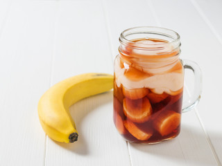 Banana in pomegranate juice with yogurt on a white table.
